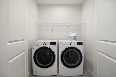 two washing machines in a white laundry room at Brand New Cozy2BR House NW Calgary DT Banff Sleep4 in Calgary