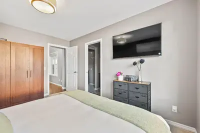 a bedroom with a large bed and a flat screen tv at Large Family Home w Kid's Play Tent! FREE Banff Pass in Calgary