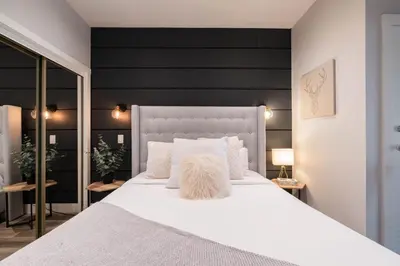 a bedroom with a white bed with a black wall at Symphony 8 by Outpost Whistler in Whistler