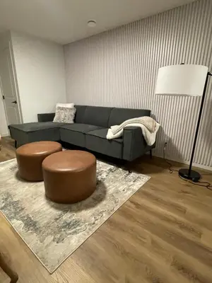 a living room with a blue couch and a brown stool at The SuiteLife, Calgary in Calgary