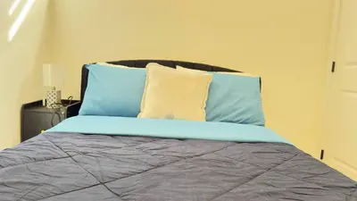 a bed with blue and yellow pillows on it at Northern Nook - 2BR Suite in Calgary