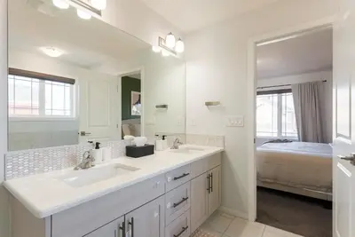 a white bathroom with a sink and a mirror at Spacious Suite in Calgary