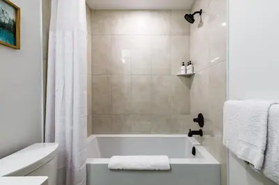 a white bathroom with a tub and a shower at Aurora Lite - Brand new suite with private entrance in Canmore