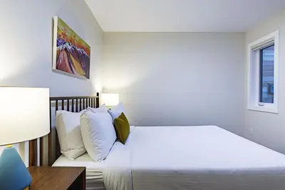 a white bedroom with a bed and a desk at Aurora Lite - Brand new suite with private entrance in Canmore