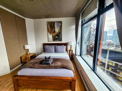 a bedroom with a bed and a large window at Historic Downtown Escape in Vancouver