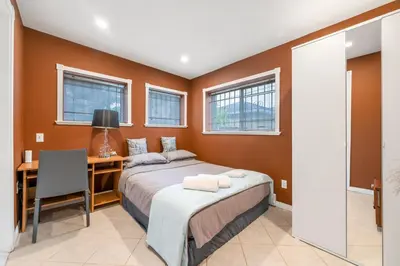 a bedroom with a bed and a desk and windows at Spacious 3BR with Full Kitchen a n dFast Wi-Fi in Vancouver
