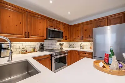 a kitchen with wooden cabinets and a stainless steel refrigerator at Blackcomb Greens 33 by Outpost Whistler in Whistler