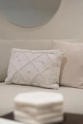 a white pillow sitting on a couch next to a table at Brand New Cozy Suite near Collingwood School in West Vancouver
