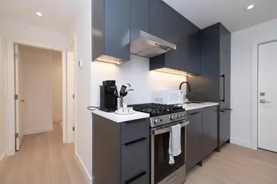 a kitchen with black cabinets and a stove top oven at Brand New Cozy Suite near Collingwood School in West Vancouver
