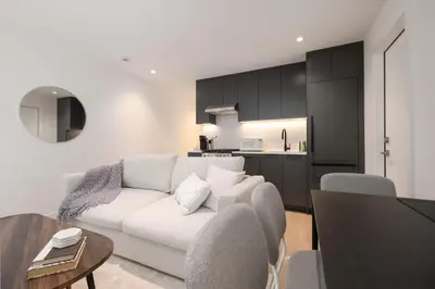 a living room with a white couch and a kitchen at Brand New Cozy Suite near Collingwood School in West Vancouver