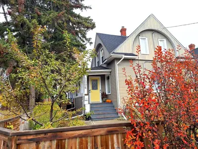 a house with a yellow door and a wooden fence at Charming Inner City Home in Calgary