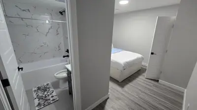 a bathroom with a toilet and a bed and a shower at Royaldee Cozy Home in Calgary