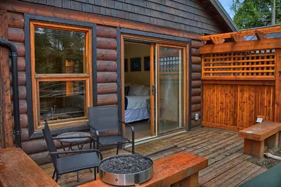 a cabin with a deck with a bed and a bedroom at Wild Renfrew Seaside Cottages in Port Renfrew