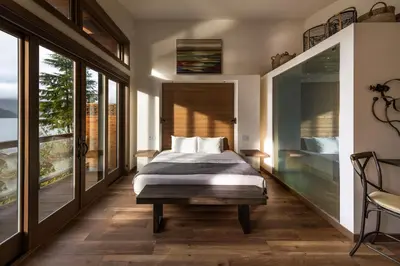 a bedroom with a bed and large windows at Wild Renfrew Seaside Cottages in Port Renfrew