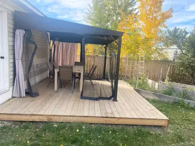 a gazebo with a table and chairs on a deck at Private Rooms in a Wonderful House in Hay River