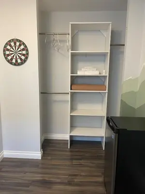 a closet with white shelves and a dartboard on the wall at Private Rooms in a Wonderful House in Hay River