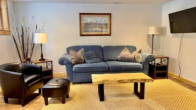 a living room with a blue couch and a tv at Suite on the Bay in Marsh Lake