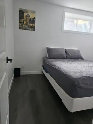 a bedroom with a bed in a white room at Affordable Comfort in Creekstone SW in Calgary