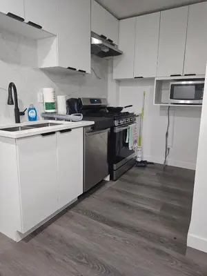 a kitchen with white cabinets and a stove top oven at Affordable Comfort in Creekstone SW in Calgary