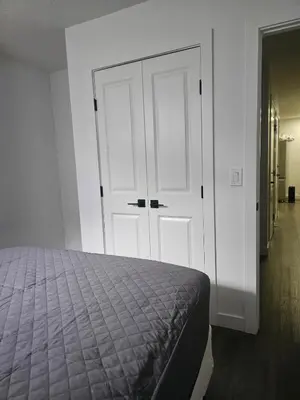 a bedroom with a bed and a white closet at Affordable Comfort in Creekstone SW in Calgary