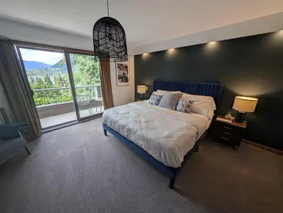 a bedroom with a large bed and a large window at Newly Renovated Shuswap Lake Cabin Multi-Family Retreat Sleeps 12 in Blind Bay