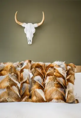 a faux fur blanket with a bull skull on the wall at Ravens Nest - Private Hot Tub in Canmore