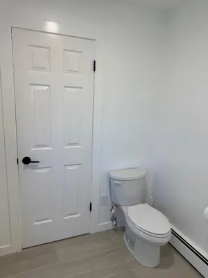 a bathroom with a white toilet and a door at Maple & Moon in Richmond