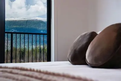 a bed with a view of the ocean from a window at Revelstoke Mountain Penthouse in Revelstoke