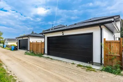 a garage with two gates on a dirt road at Luxury Home Near DT, New Build, High-End Features in Calgary