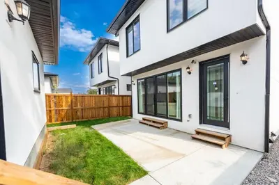 a backyard of a white house with a wooden fence at Luxury Home Near DT, New Build, High-End Features in Calgary