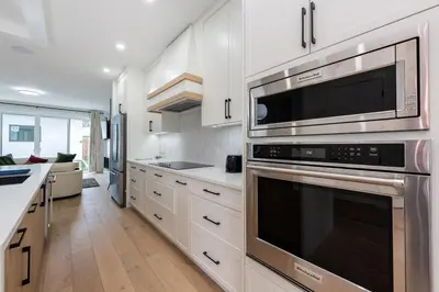 a kitchen with stainless steel appliances and white cabinets at Luxury Home Near DT, New Build, High-End Features in Calgary