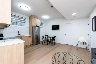 a kitchen with a refrigerator and a table with chairs at Newly built 2 bedroom suite with kitchen & laundry in Calgary