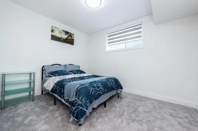 a bedroom with a bed and a window at Newly built 2 bedroom suite with kitchen & laundry in Calgary