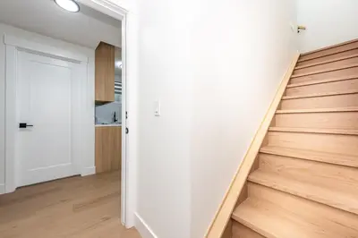 an open hallway with stairs and a white door at Newly built 2 bedroom suite with kitchen & laundry in Calgary