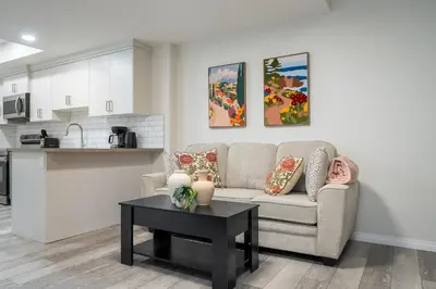 a living room and kitchen with a couch and a table at 2BR Stylish & Private Suite SE! FREE Banff Pass, Netflix, Parking! in Calgary
