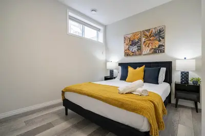 a bedroom with a large bed with yellow and blue pillows at 2BR Stylish & Private Suite SE! FREE Banff Pass, Netflix, Parking! in Calgary