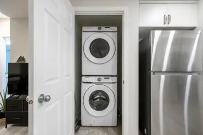 a kitchen with a washing machine and a refrigerator at 2BR Stylish & Private Suite SE! FREE Banff Pass, Netflix, Parking! in Calgary