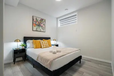a bedroom with a large bed with orange pillows at 2BR Stylish & Private Suite SE! FREE Banff Pass, Netflix, Parking! in Calgary