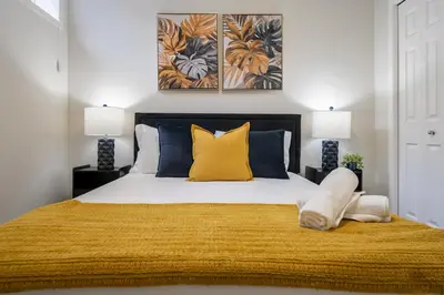 a bedroom with a bed with yellow and blue pillows at 2BR Stylish & Private Suite SE! FREE Banff Pass, Netflix, Parking! in Calgary
