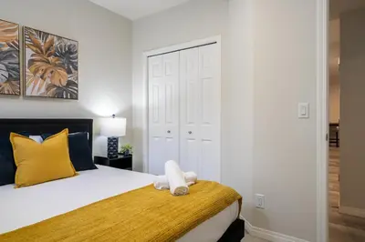a bedroom with a bed with a yellow and white pillow at 2BR Stylish & Private Suite SE! FREE Banff Pass, Netflix, Parking! in Calgary