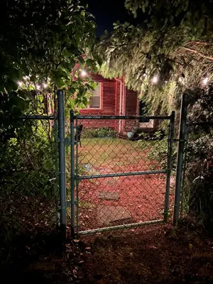 a fence with a gate in front of a house at Studio Cedar Guest Cottage in Duncan