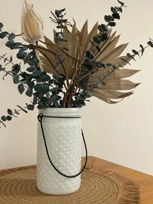 a white vase with a plant in it on a table at Studio Cedar Guest Cottage in Duncan