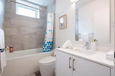 a white bathroom with a tub and a sink and a toilet at Relaxing 2BR Stay - Kitchen & Central Convenience in Vancouver