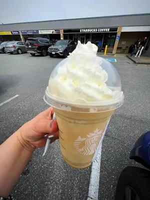 a hand holding a plastic cup with whipped cream at Relaxing 2BR Stay - Kitchen & Central Convenience in Vancouver