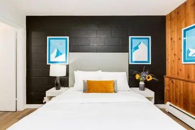 a bedroom with a large white bed with a black wall at Gateway Suites Rocky Mountains stay near Banff in Canmore