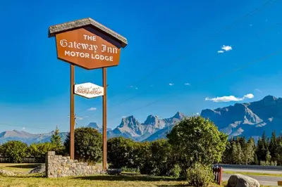 a sign for the gibraltar inn motor lodge with mountains in the background at Gateway Suites Rocky Mountains stay near Banff in Canmore