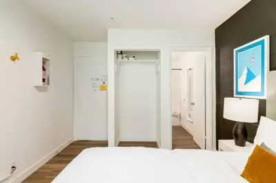 a bedroom with a white bed with a blue painting on the wall at Gateway Suites Rocky Mountains stay near Banff in Canmore