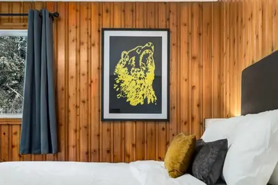 a picture hanging on a wooden wall next to a bed at Gateway Suites Cozy stay to explore Banff and Canmore in Canmore