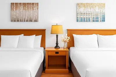 two beds in a hotel room with a table with a lamp at Mini Getaway with Mountain Views Near Banff in Canmore
