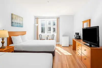 a hotel room with two beds and a flat screen tv at Mini Getaway with Mountain Views Near Banff in Canmore